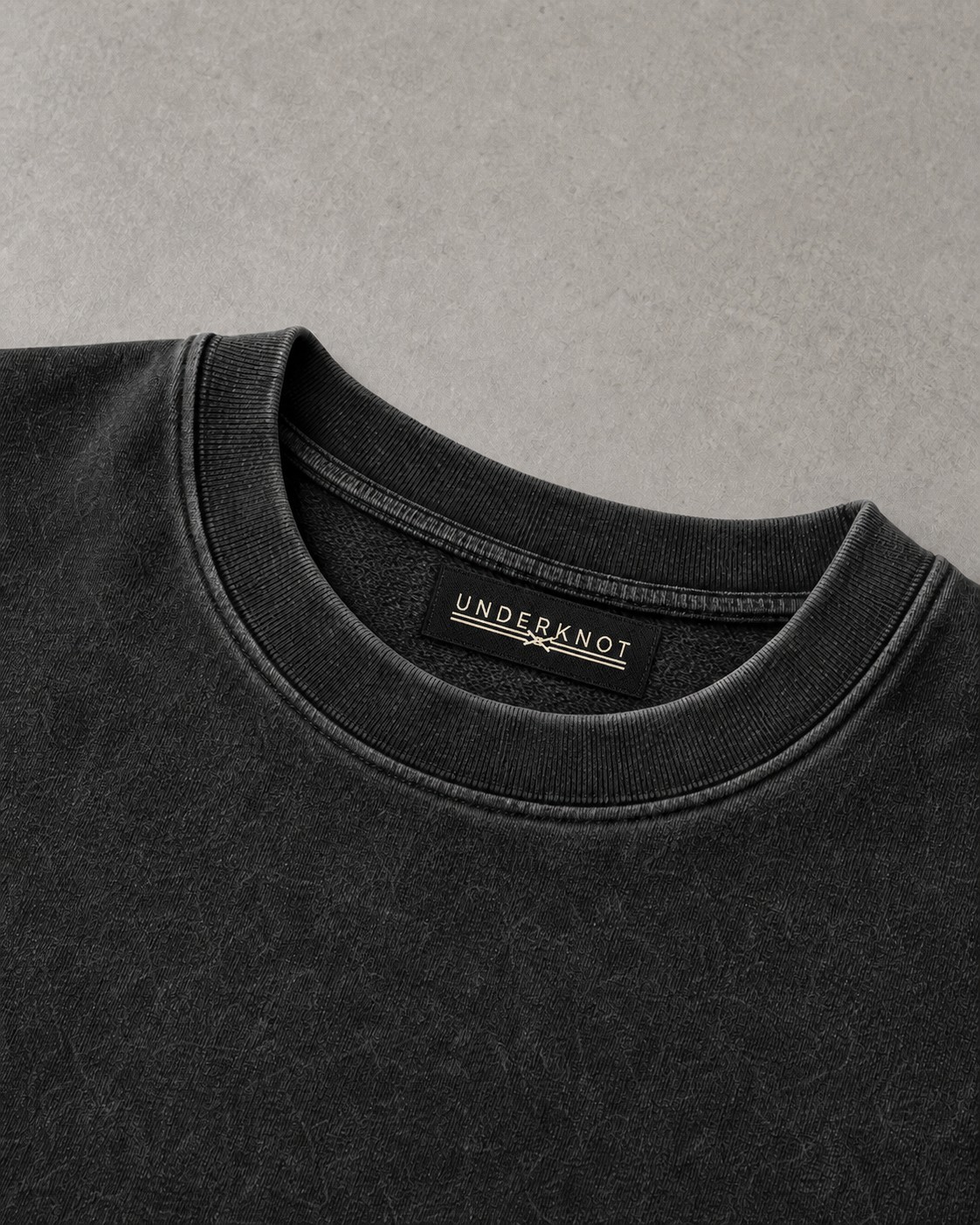 HEAVYWEIGHT POCKET TEE 넥 안쪽 중앙의 블랙 직조 UNDERKNOT 메인라벨과 웜 에크루 엠블럼을 보여 주는 디지털 디테일. 사이즈 표기 없음